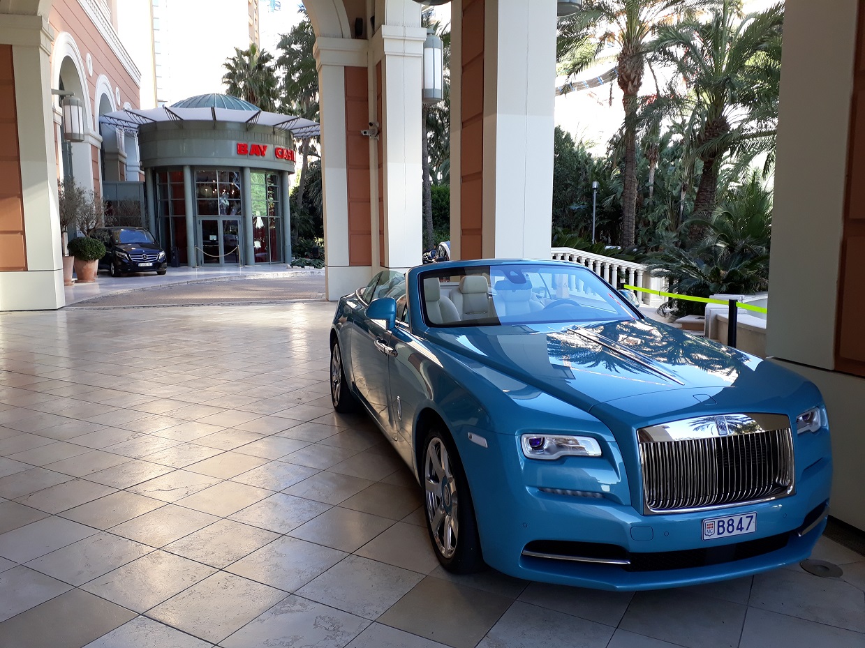 Eine blaue Luxuslimousine steht in einem Säulengang.